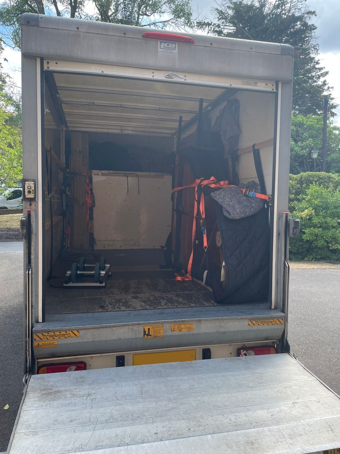 Grand piano securely loaded and strapped inside the back of a luton van.